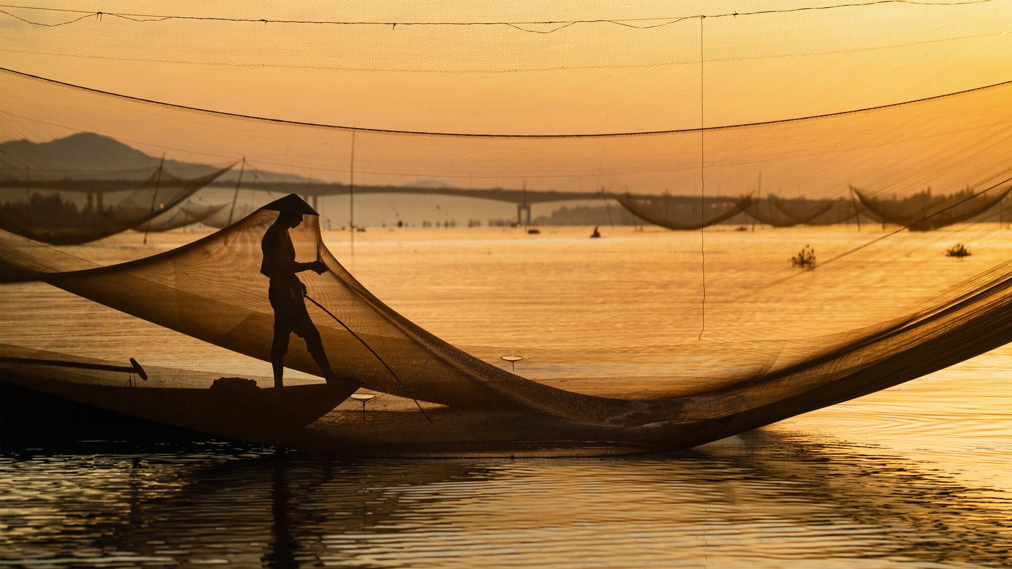 Fisherman casting net at sunrise on the Thu Bon river